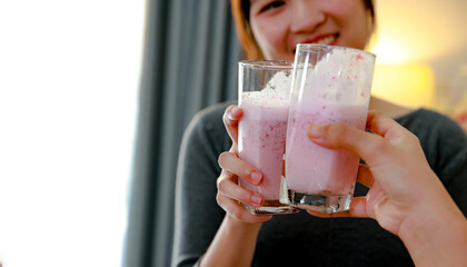 Two teenage Asian girls happily make refreshing strawberry and banana smoothies in their home kitchen creating unique and delicious recipe. © ฺฺฺBoonterm
