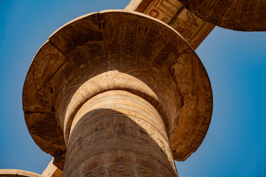 Epic Karnak temple ancient Egyptian architecture hypostyle hall panorama. 
Cinematic low angle view of historic Luxor sandstone columns, 
carved pharaoh hieroglyphs bas relief and blue sky.
