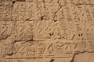 Fototapeta premium Epic ancient Egyptian hieroglyphs stone texture background. Cinematic horizontal pattern of historic sandstone wall surface with carved pharaoh cartouche, antique mythology symbols and hard shadow c