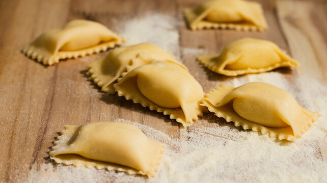 Handmade agnolotti del plin on wooden board, close up detail, Italian cuisine