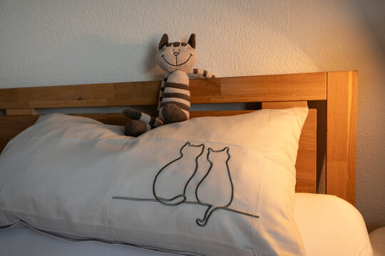 Katzenkultur im Schlafzimmer  - ein besticktes Kopfkissen mit Katzenmotiv und eine Katze aus Stoff