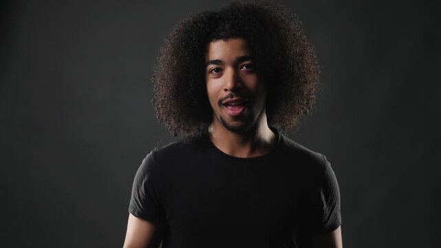 A confident young man with afro hair looks directly at the camera, portraying a serious and composed expression. This studio portrait highlights diversity and authenticity, projects focusing on youth,