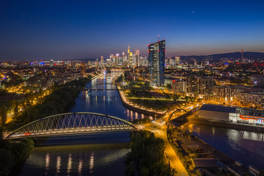 Aerial view of the ECB Tower and the illuminated skyline overlooking the Main river and bridges at night Frankfurt am Main, Hessen, Germany.