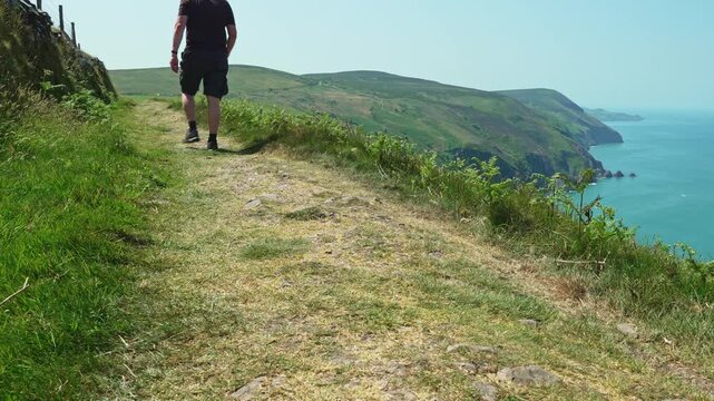 Male walking on the coast path near Haddon&rsquo;s Mouth, Devon, England