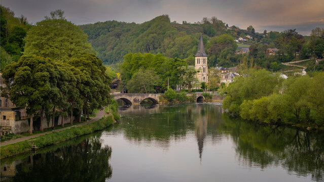 Aerial view of the Meuse river flowing past the historic town center with the Collegiate Church spire and lush green hills Dinant, Wallonia, Belgium.
