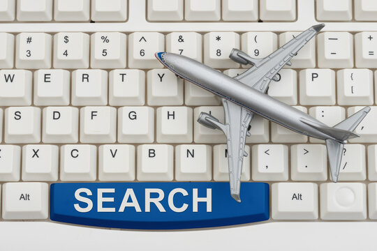 Search text with an airplane on a white computer keyboard for booking a flight online