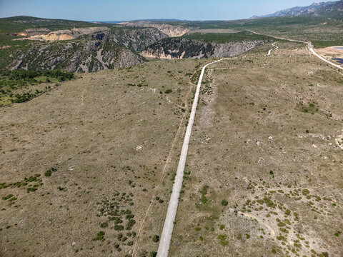 Aerial view of a winding road stretching through a rugged rocky landscape near the Zrmanja canyon under a clear blue sky Zaton Obrovacki, Zadar County, Croatia.