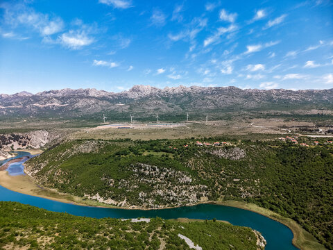 Aerial view of Suncana elektrana Obrovac solar power plant and wind turbines near the Zrmanja river canyon with the Velebit mountains in Zaton Obrovacki, Zadar County, Croatia.