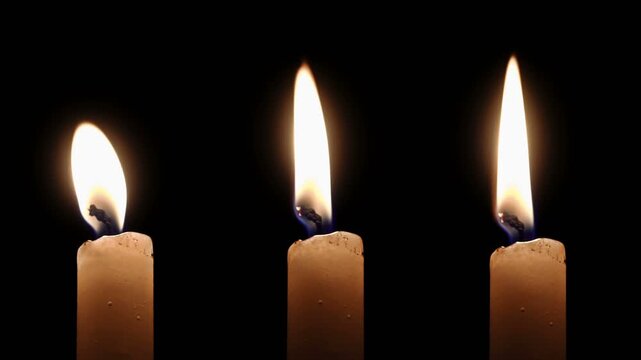 Four White Taper Candles Burning at Different Heights on Black background
