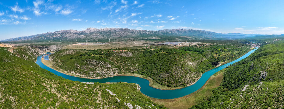 Aerial view of the winding Zrmanja River flowing through a canyon near the Suncana elektrana Obrovac solar power plant in Zaton Obrovacki, Zadar County, Croatia.