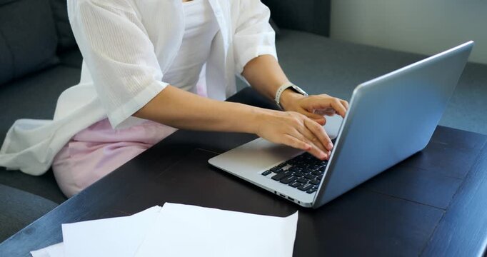 Lady reviewing bills on computer. Woman engaged in financial management with documents and laptop. Individual focused on accounting tasks involving paperwork and digital records at residence