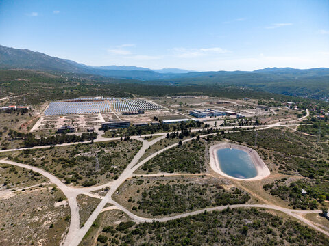 Aerial view of the Suncana elektrana Obrovac solar power plant with rows of photovoltaic panels and a water reservoir in Zaton Obrovacki, Zadar County, Croatia.