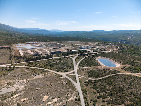 Aerial view of Suncana elektrana Obrovac solar power plant with rows of panels and a water reservoir among rugged hills in Zaton Obrovacki, Zadar County, Croatia.