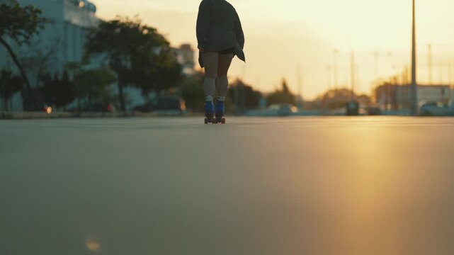 Young woman roller skating towards sunset in the city