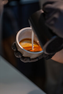Barista pouring steamed milk into coffee cup for latte art