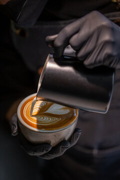 Barista finishing beautiful rosetta latte art in a ceramic cup