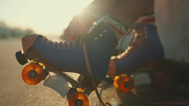 Close-up of woman tying vintage roller skates at sunset