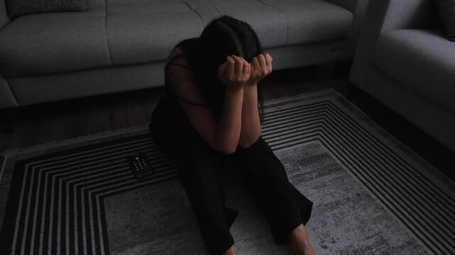 Young woman sitting alone after messaging, feeling ignored and ghosted, concept of digital heartbreak and loneliness in home interior, emotional breakdown