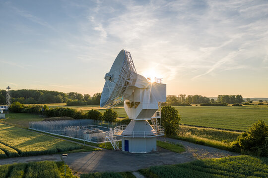 Aerial view of the Leeheim Satellite Monitoring Station with its large parabolic antenna surrounded by green fields and trees during a golden sunset Riedstadt, Hessen, Germany.