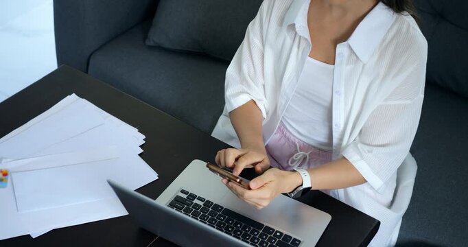 Lady effectively coordinates electronic communications with manual documentation amidst chaos. Woman proficiently juggles multiple gadgets and paperwork in busy and chaotic setting