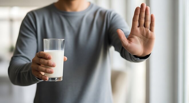 Man holding glass of milk and gesturing no or refusal with hand