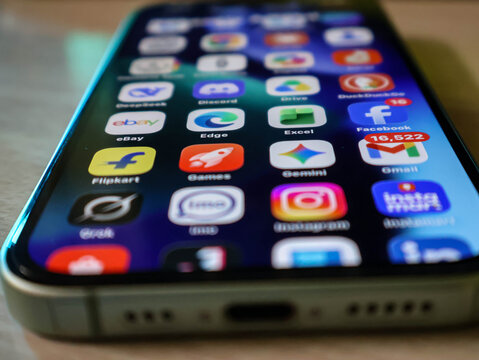 Closeup of a modern smartphone screen displaying various popular mobile application icons on a blurred background