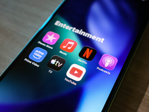 Closeup of a iPhone screen displaying an entertainment folder with various popular streaming and media application icons