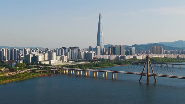 Aerial descent above Han River with view of Olympic Bridge and Lotte World Tower rising over Songpa District skyline in Seoul South Korea