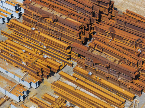 Aerial view of stacks of rusty and painted steel I-beams organized in an industrial storage yard in Taiwan.