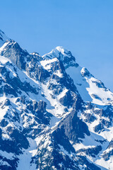 Obraz premium Snow Covered Rocky Mountain Peaks Under Blue Sky