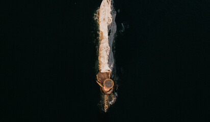 Top-down aerial view of a lighthouse on a narrow rocky reef © Reuben