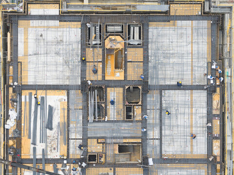 Aerial view of a building foundation under construction with workers installing steel rebar grids and concrete forms on a large site in Taiwan.