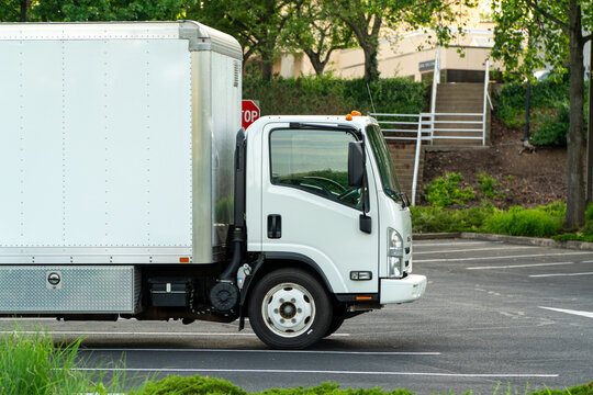 Clean white commercial box truck parked in an asphalt lot, ready for urban or suburban deliveries and moving services. Represents efficient logistics, transportation, and cargo shipping solutions.