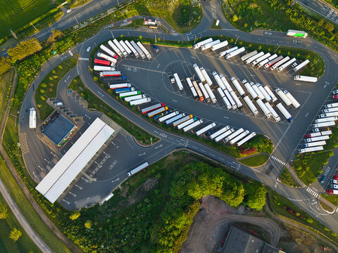 Aerial view of Rugby Services with rows of parked trucks and lorries surrounded by lush green trees and fields Rugby, England, United Kingdom.