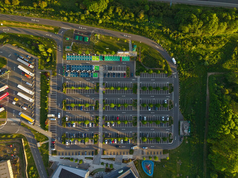Aerial view of Rugby Services with organized parking bays and rows of trees surrounded by lush greenery in Rugby, England, United Kingdom.