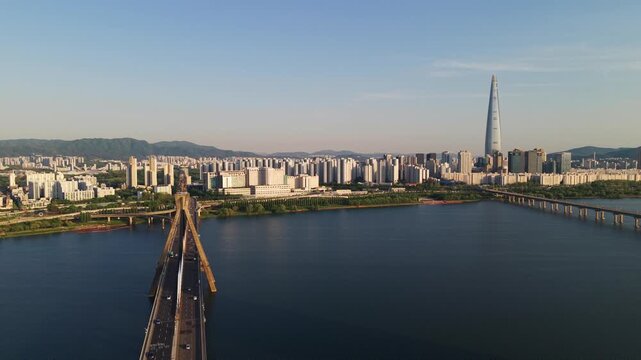 Aerial parallax above Olympic Bridge cable-stayed pylon with busy traffic at sunset and Lotte Tower over Han River in Seoul South Korea
