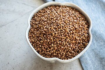 Obraz premium Fresh organic uncooked buckwheat in gray plate on the table for cooking.