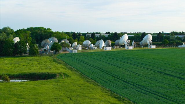 Aerial view of the Satellite Mediaport featuring multiple large parabolic antennas surrounded by lush green fields and trees in Long Lawford, England, United Kingdom.