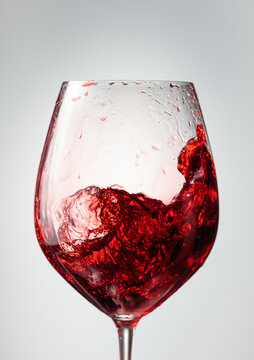 Wine glass with red liquid frozen in movement.