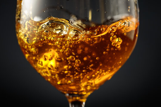 White wine of rich amber color being poured into a glass.