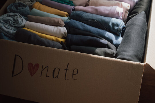 Box of neatly folded clothes ready for donation at home, highlighting generosity and community spirit on a sunny day