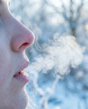 Woman profile breathing winter cold air outdoors close up visible breath steam frost weather nature background