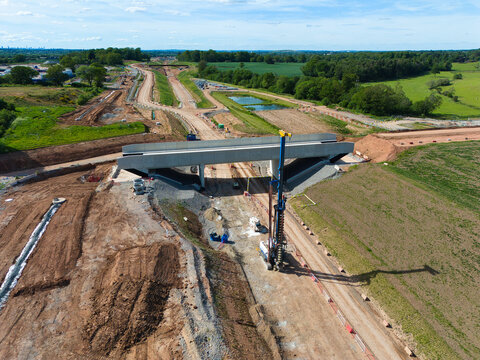 Aerial view of HS2 Civil Engineering Works featuring a concrete bridge structure and heavy machinery under a blue sky Balsall Common, England, United Kingdom.