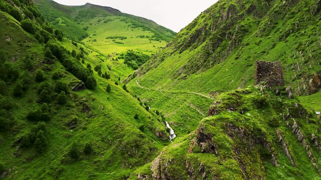 Epic Gergeti canyon mountain river valley aerial flight. 
Cinematic drone forward tracking shot inside deep gorge 
along wild stream near Kazbegi historic church in Georgia.
