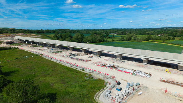 Aerial view of HS2 Civil Engineering Works showing a long concrete viaduct under construction amidst green fields and construction equipment in Hampton in Arden, England, United Kingdom.