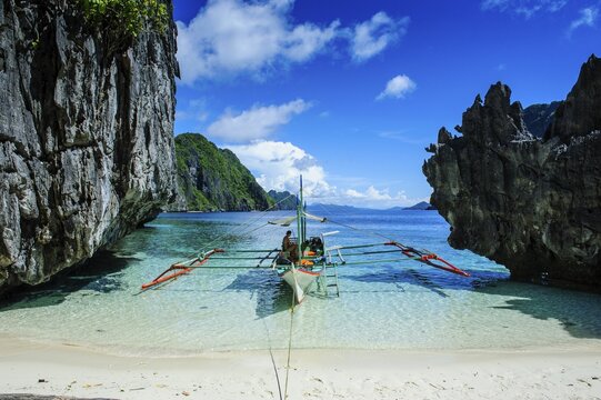 Outrigger boat on a little white beach and crystal clear water in the Bacuit archipelago, Palawan, Philippines