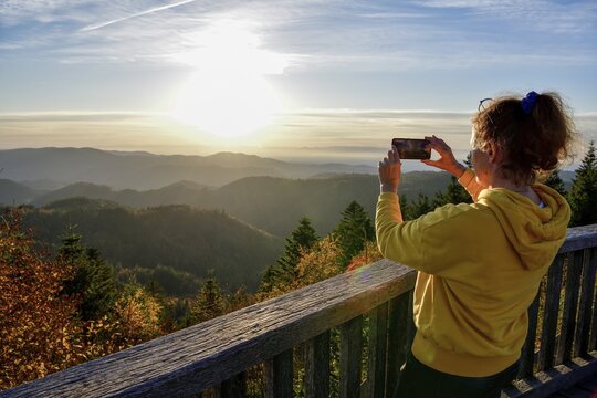 Woman photographing the sunset at Schliffkopf, near Baiersbronn, Freudenstadt district, Black Forest, Baden-W&uuml;rttemberg, Germany