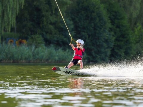 Boy or girl with wakeboard in the lake, water sports, water skiing in the wake park