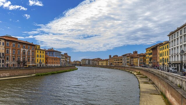 Rows of houses with pastel-coloured facades to the left and right of the River Arno, Pisa, Tuscany, Italy