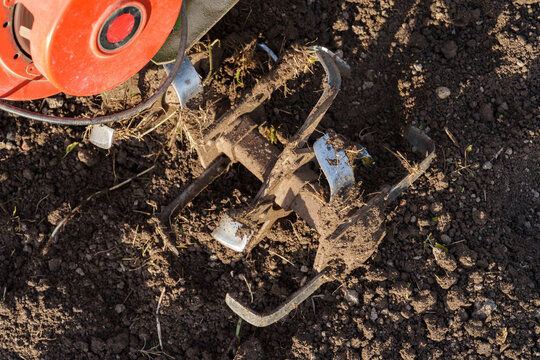 Rotary tiller blades cultivating soil close up